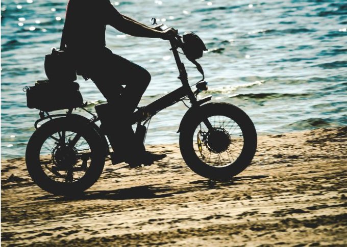 Mężczyzna jeździ po plaży na rowerze elektrycznym